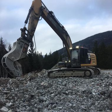 Gravemaskin står på en haug av steiner